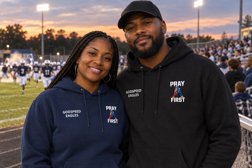 Couple wearing Godspeed Eagles hoodies as players run onto the field